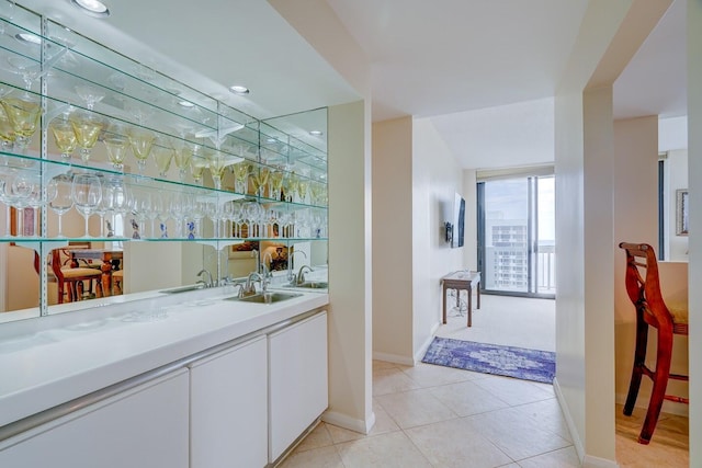 bar featuring light tile patterned floors, white cabinetry, and sink