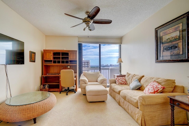 living room featuring carpet flooring, ceiling fan, and a textured ceiling