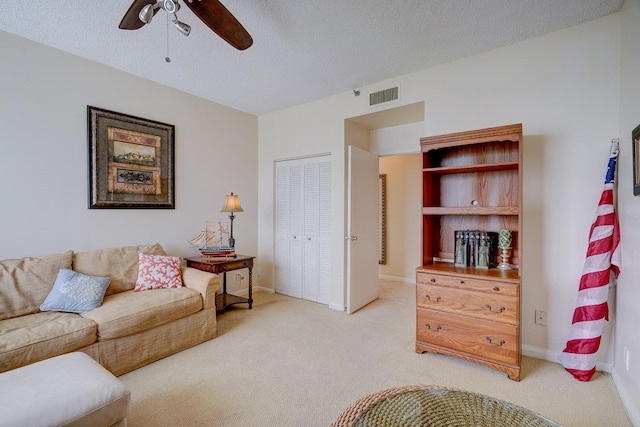 living room with ceiling fan, light colored carpet, and a textured ceiling