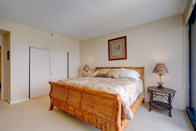 bedroom with a textured ceiling, light carpet, and a closet