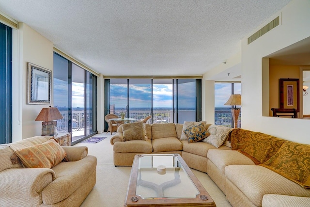 living room with a wealth of natural light, light colored carpet, a textured ceiling, and a wall of windows