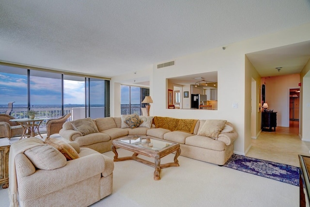 living room featuring floor to ceiling windows, a textured ceiling, a water view, and ceiling fan