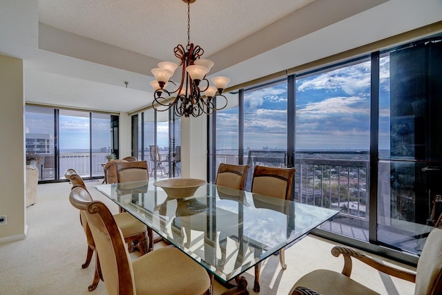 dining space with a textured ceiling, light colored carpet, expansive windows, and a notable chandelier