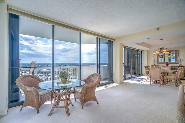 dining space with floor to ceiling windows, light colored carpet, and a notable chandelier