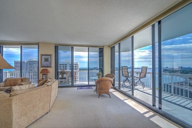 carpeted living room featuring a textured ceiling, a water view, and floor to ceiling windows