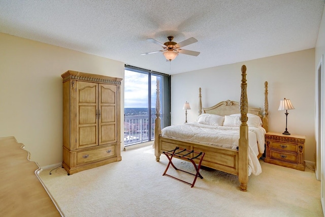 bedroom with floor to ceiling windows, light carpet, access to outside, ceiling fan, and a textured ceiling