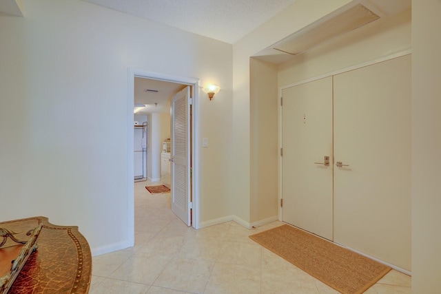 hall featuring light tile patterned floors and a textured ceiling