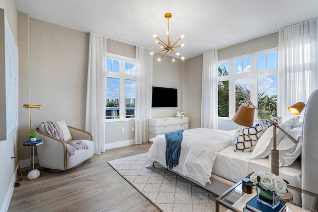 bedroom with multiple windows, light hardwood / wood-style floors, and an inviting chandelier