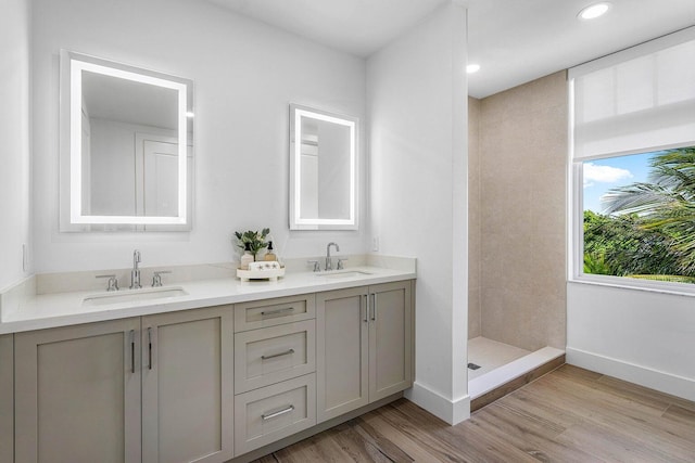 bathroom featuring tiled shower, wood-type flooring, and vanity