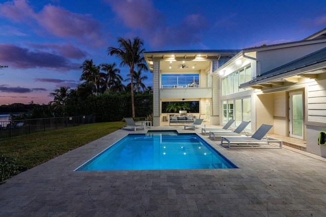 pool at dusk with a patio and an outdoor hangout area