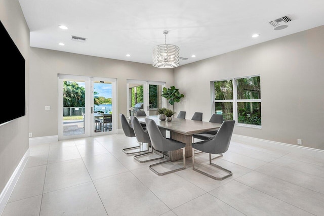 tiled dining area featuring a chandelier and french doors