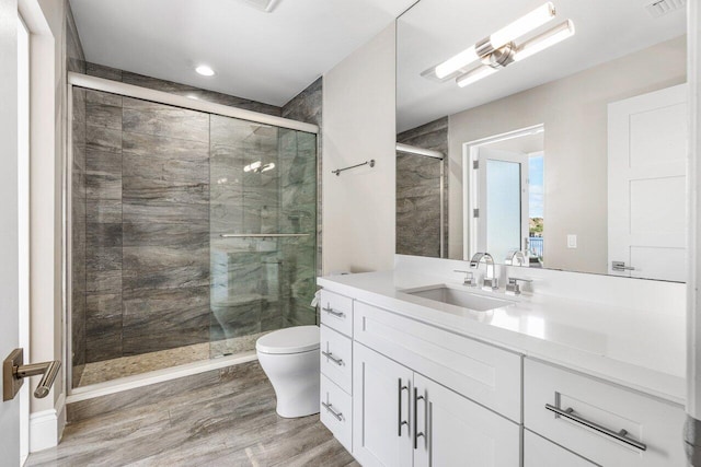 bathroom with hardwood / wood-style floors, vanity, toilet, and a shower with shower door