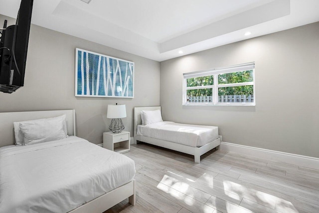 bedroom with a tray ceiling and light hardwood / wood-style flooring