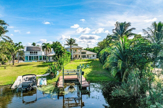 view of dock with a lawn and a water view