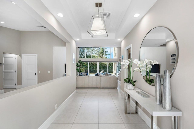 corridor featuring light tile patterned floors and a tray ceiling