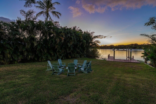 yard at dusk featuring a water view and a boat dock