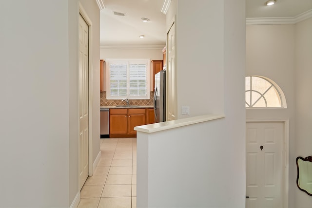 hall with light tile patterned flooring, ornamental molding, and sink