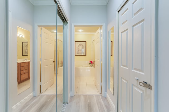 hallway with light wood-type flooring and crown molding