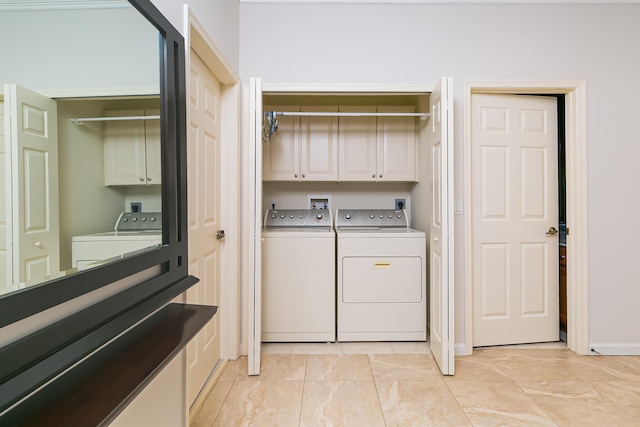 clothes washing area with cabinets and washer and dryer