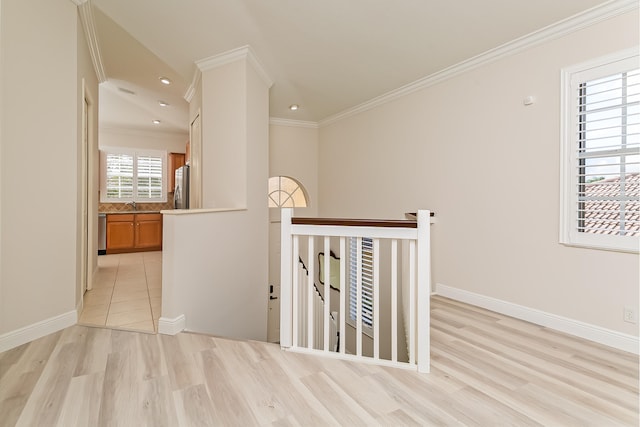 corridor featuring light wood-type flooring, crown molding, and sink