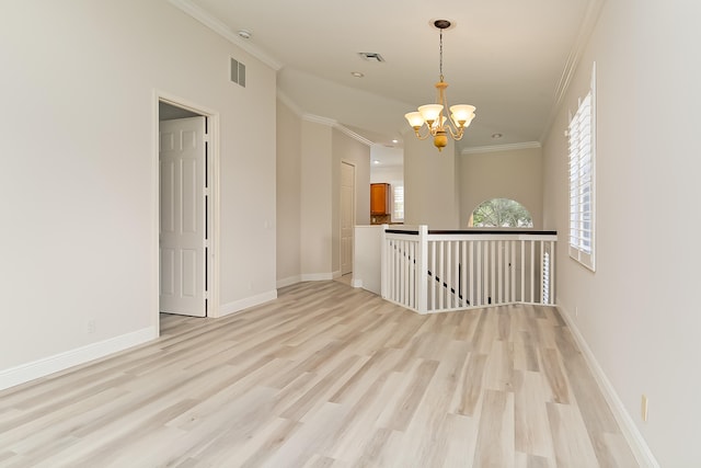 empty room featuring a chandelier, light hardwood / wood-style flooring, and ornamental molding