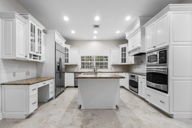 kitchen with a center island, sink, built in appliances, white cabinetry, and dark stone counters