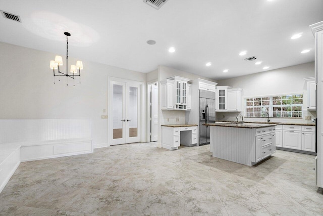 kitchen featuring an inviting chandelier, stainless steel built in fridge, hanging light fixtures, white cabinets, and a center island