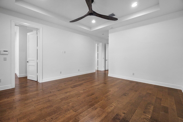 unfurnished room featuring ceiling fan, dark wood-type flooring, and a tray ceiling