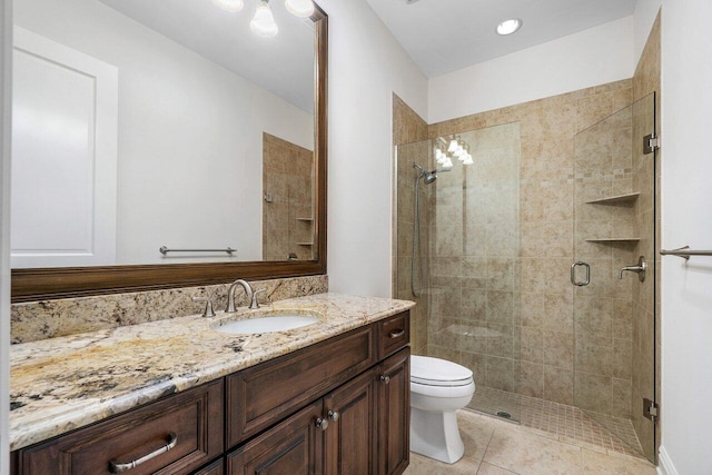 bathroom featuring toilet, vanity, tile patterned floors, and a shower with door