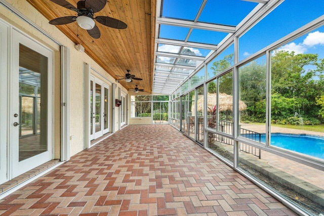 unfurnished sunroom with wooden ceiling, a healthy amount of sunlight, and ceiling fan