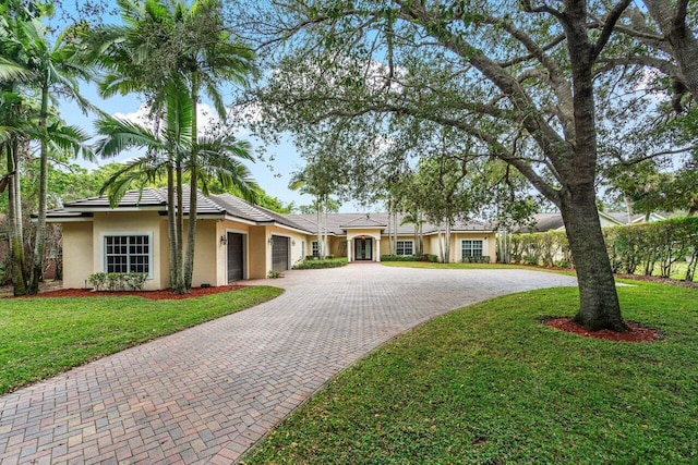 ranch-style house featuring a garage and a front lawn