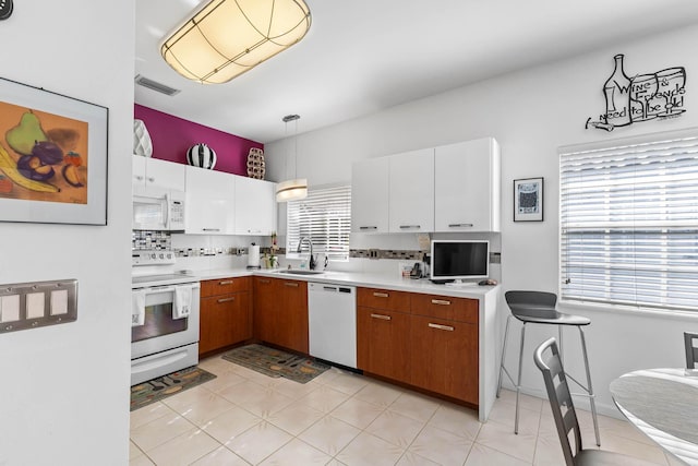 kitchen with white appliances, sink, tasteful backsplash, decorative light fixtures, and white cabinetry