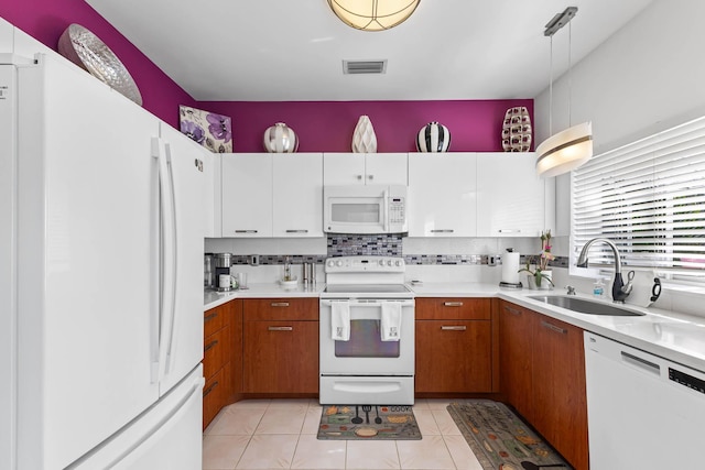 kitchen featuring sink, white cabinets, light tile patterned flooring, and white appliances