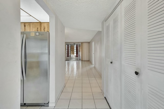 corridor with light tile patterned flooring and a textured ceiling