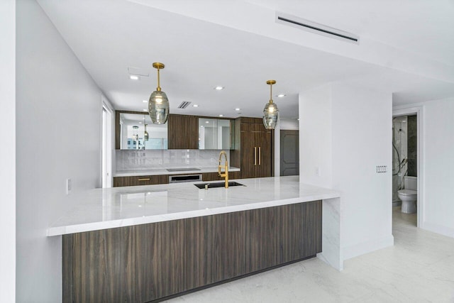 kitchen with pendant lighting, backsplash, kitchen peninsula, and sink