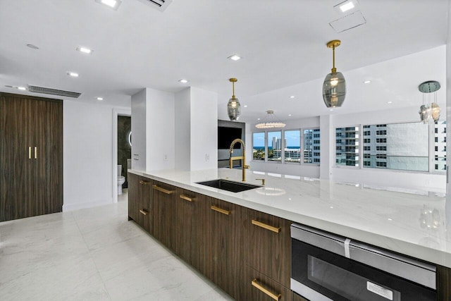 kitchen featuring light stone countertops, sink, and hanging light fixtures