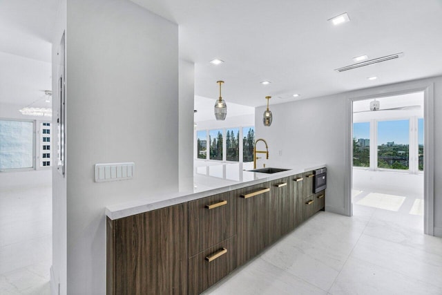 kitchen featuring stainless steel microwave, sink, oven, and decorative light fixtures