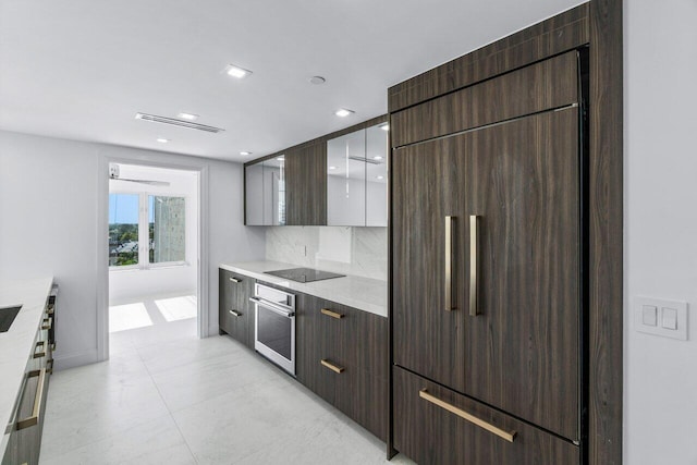 kitchen featuring decorative backsplash, light stone countertops, black electric stovetop, stainless steel oven, and paneled fridge