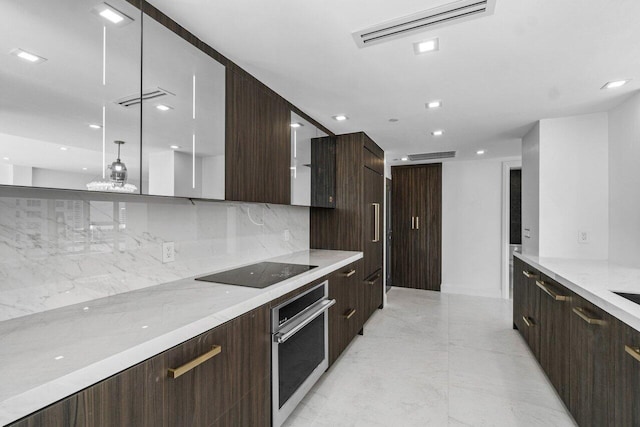 kitchen with stainless steel oven, tasteful backsplash, light stone counters, decorative light fixtures, and black electric cooktop