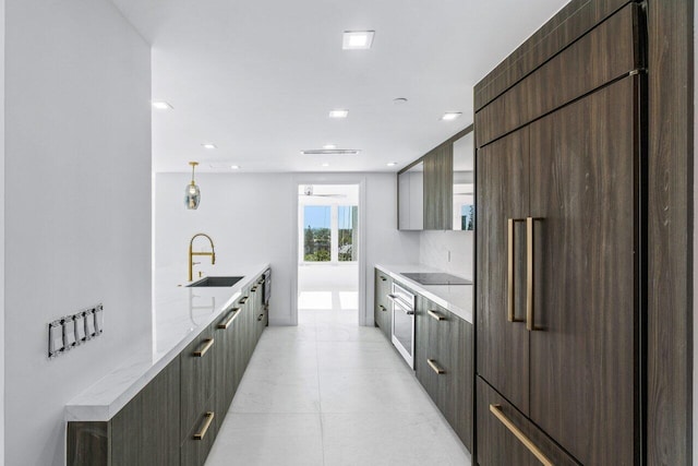 kitchen with light stone counters, sink, paneled fridge, and black electric stovetop