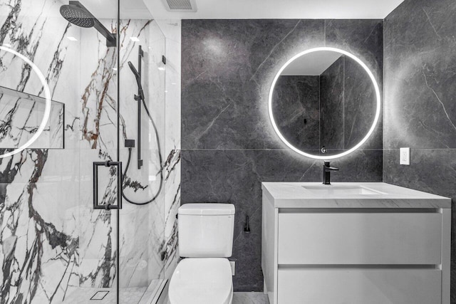 bathroom with vanity, toilet, tile walls, and a shower with shower door