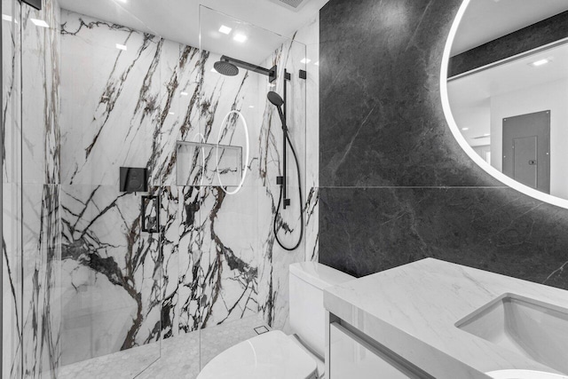 bathroom featuring a tile shower, vanity, toilet, and tile walls