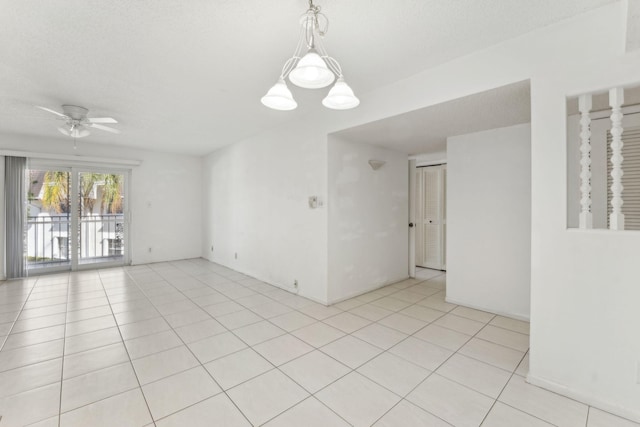 unfurnished room featuring a textured ceiling, light tile patterned flooring, and ceiling fan with notable chandelier