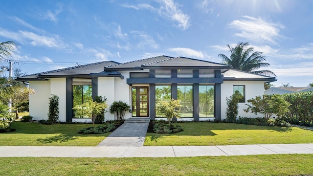 view of front of house with a tile roof, a front lawn, french doors, and stucco siding