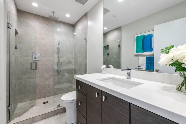 bathroom with tile patterned floors, vanity, toilet, and walk in shower