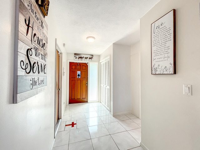 corridor featuring light tile patterned floors and a textured ceiling