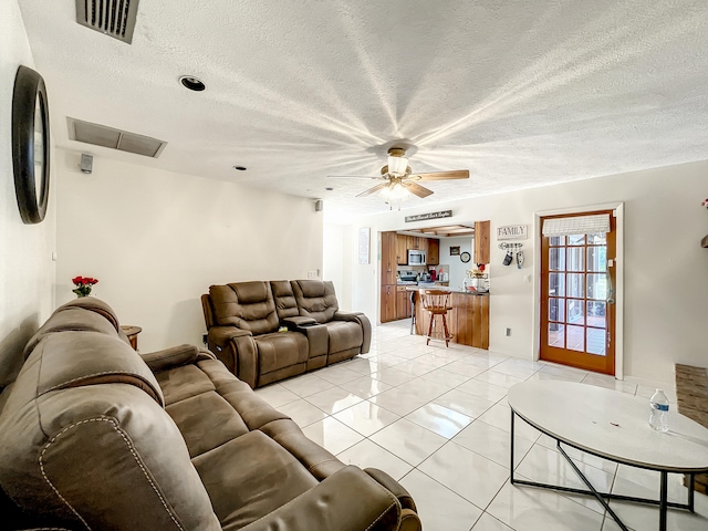 tiled living room with ceiling fan and a textured ceiling