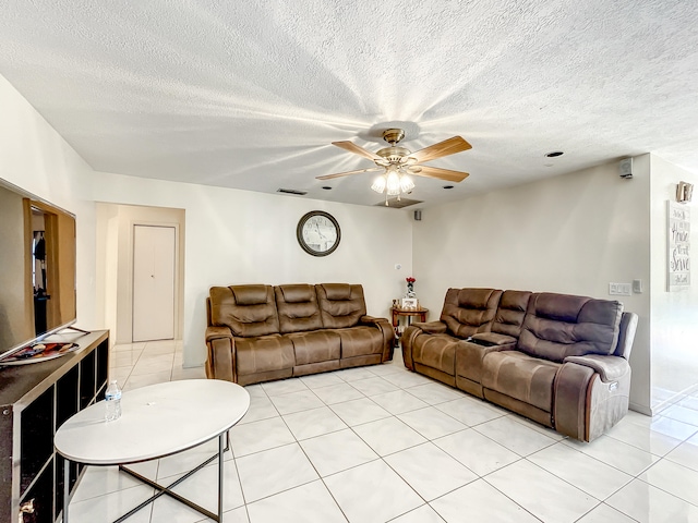 living room featuring ceiling fan, light tile patterned floors, and a textured ceiling