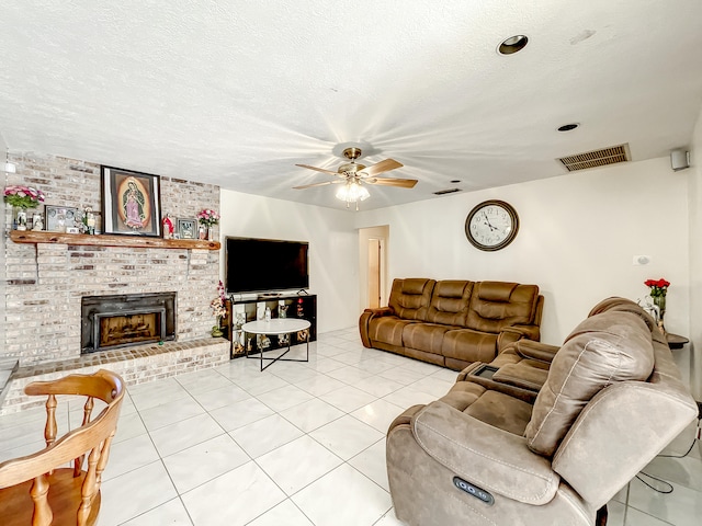 living room featuring ceiling fan, a fireplace, light tile patterned floors, and a textured ceiling