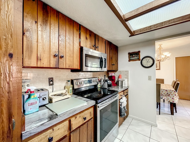 kitchen featuring decorative backsplash, light tile patterned floors, decorative light fixtures, stainless steel appliances, and a chandelier